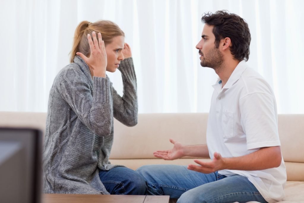 Casal cristão em momento de crise, com a mulher expressando preocupação e o homem pensativo, ilustrando os desafios e desentendimentos em um relacionamento.